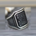 Black alloy ring with copper inlay details and a central sparkling zircon stone on a plain background.