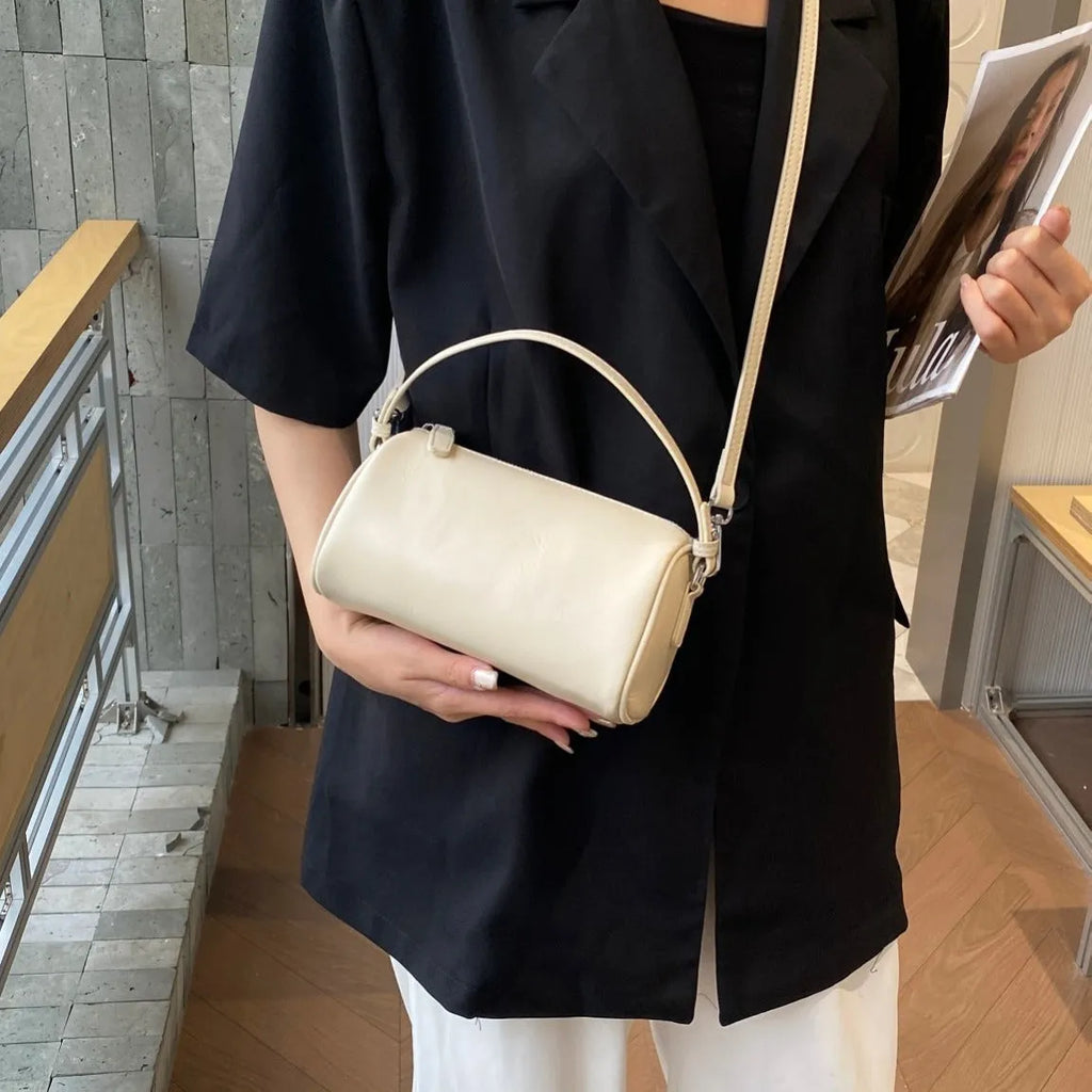 Cylindrical crossbody phone bag in soft genuine leather, shown in one of six colours including black or brown.