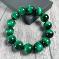 Green Tiger Eye stone bracelet with round polished beads on a wrist.