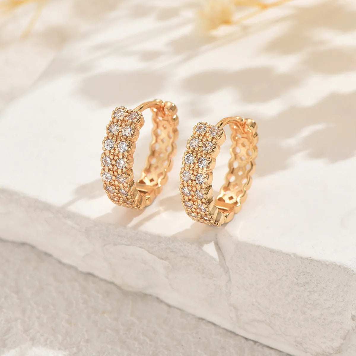 A pair of women's geometric pattern ear studs made from copper, showing round, dot, and ring design details.