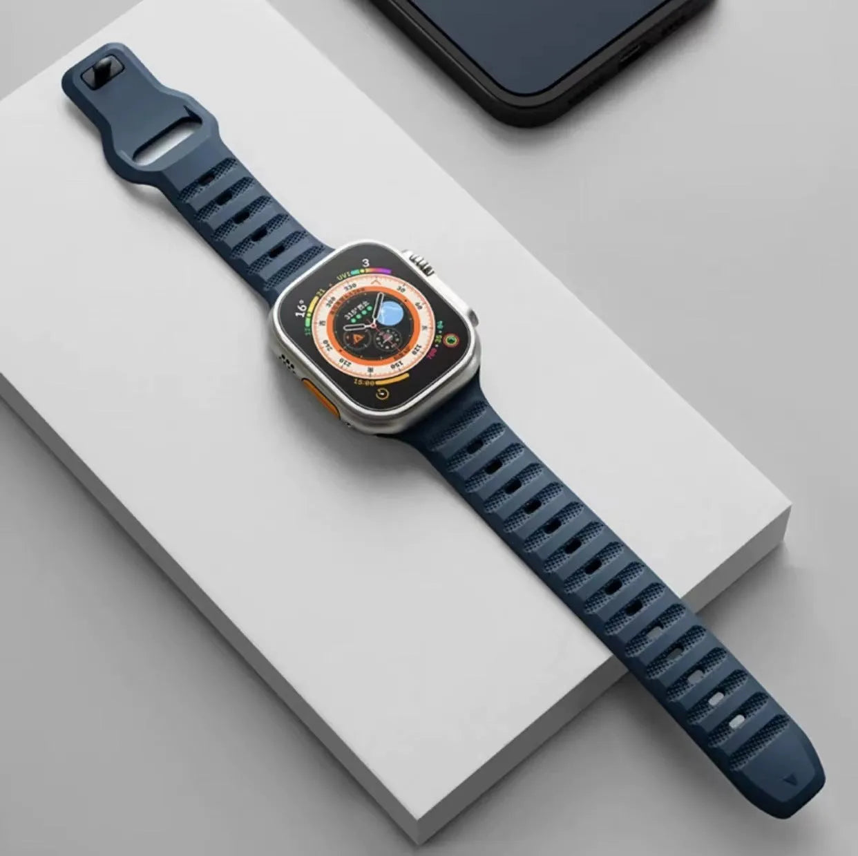 Black fluoro rubber Apple Watch strap with T-buckle closure shown detached from watch.