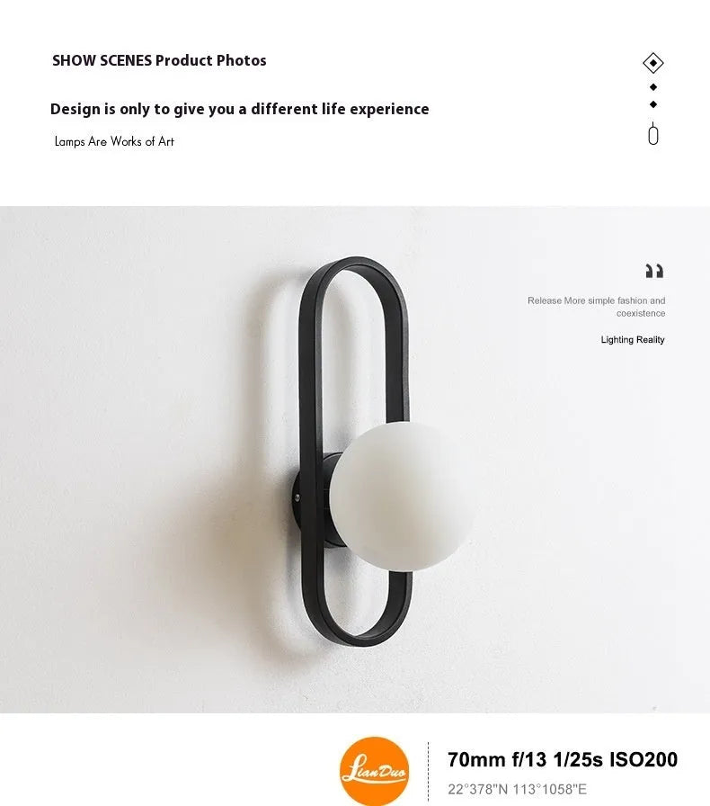 Minimalist wall-mounted lamp with clear glass bulb shade on a black iron sconce arm and backplate.
