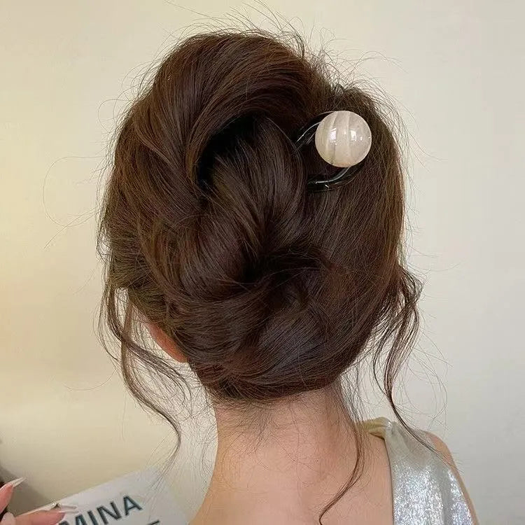 A set of U-shaped acrylic hair barrettes with a ball detail in beige, caramel, dark grey, and green colours