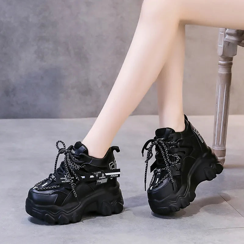 Women's white and black platform sports shoes with cross strap and rubber sole.
