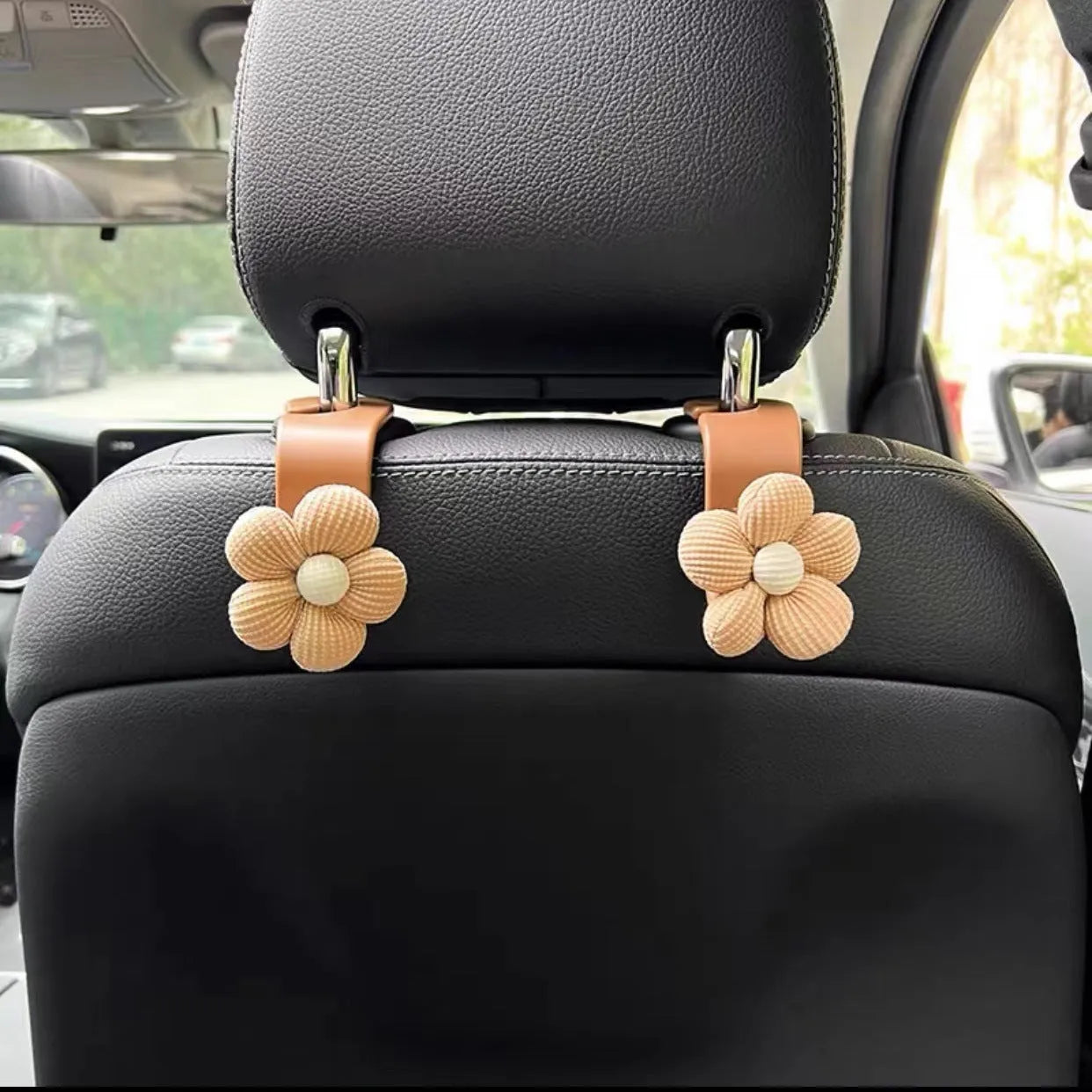 Khaki-coloured plastic car seat hook with a small decorative flower for storage.