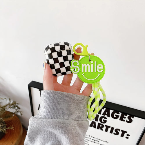Black and green checkerboard pattern TPU protective case sleeves for Apple AirPods, one with a smiley face lanyard attached.