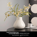 Black ceramic round belly French decorative vase with artificial flower stems on wooden surface