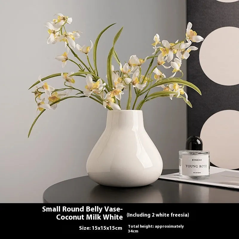 Black ceramic round belly French decorative vase with artificial flower stems on wooden surface