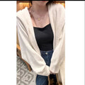 A woman wearing a long, loose, beige hooded knitted cardigan in a Korean casual style.
