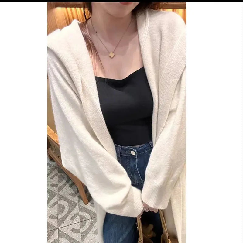 A woman wearing a long, loose, beige hooded knitted cardigan in a Korean casual style.