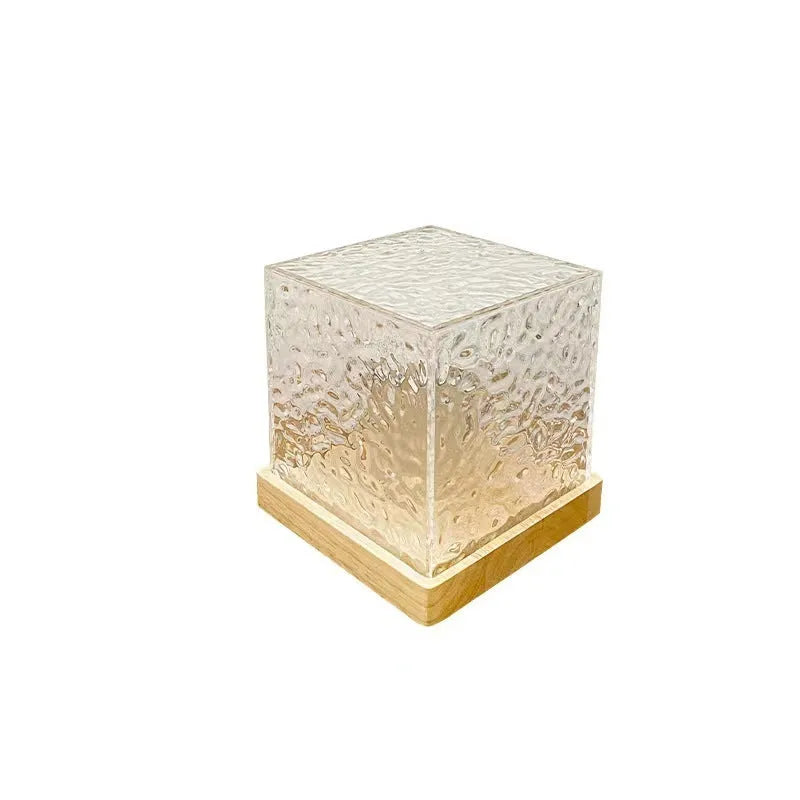 Modern geometric crystal table lamp projecting blue water ripple light pattern on a wall.