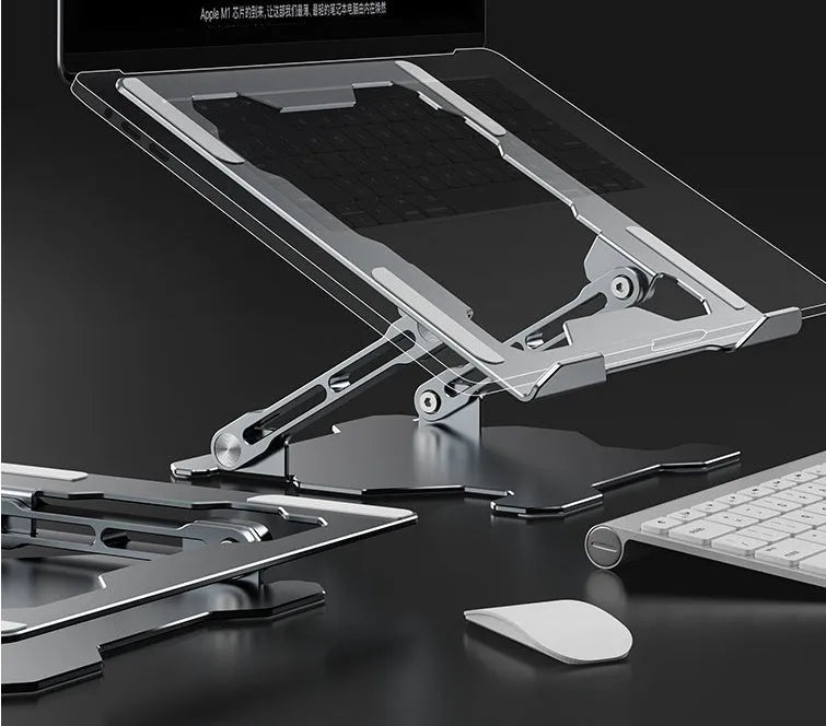 Grey aluminium laptop stand in a folded position next to an open laptop, showing its adjustable angle and hollow design.