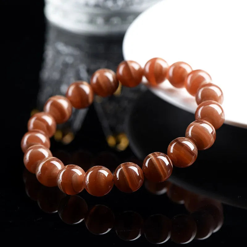 Natural Old Mine Rhodochrosite round bead bracelet on wrist, showing manganese spar colour.