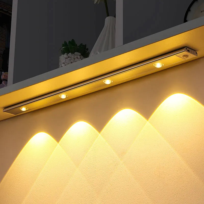 Silver ultra-thin wireless LED strip light with motion sensor attached to a kitchen cabinet door.