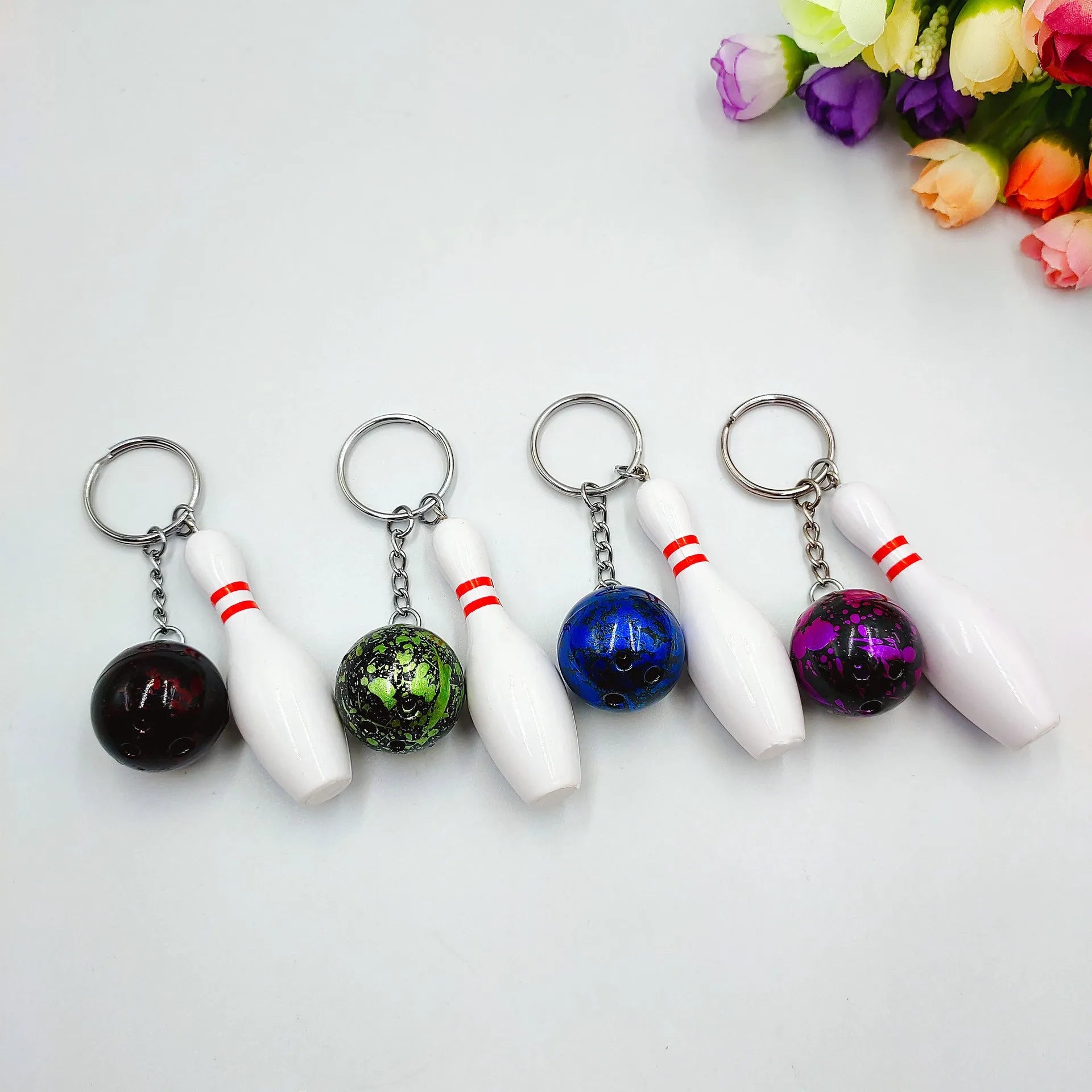 Mini bowling ball keychain in four colour options: dark red, blue, purple, green