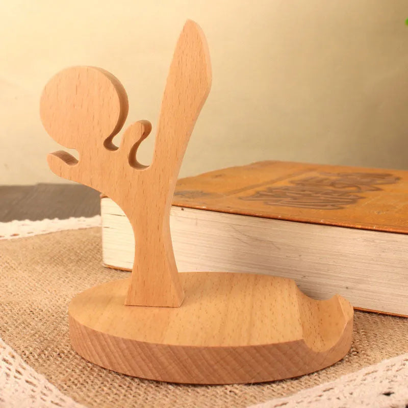 Solid beech wood phone stand with a decorative resin puppy figurine, holding a mobile phone at an angle with a charging cable threaded through the back.