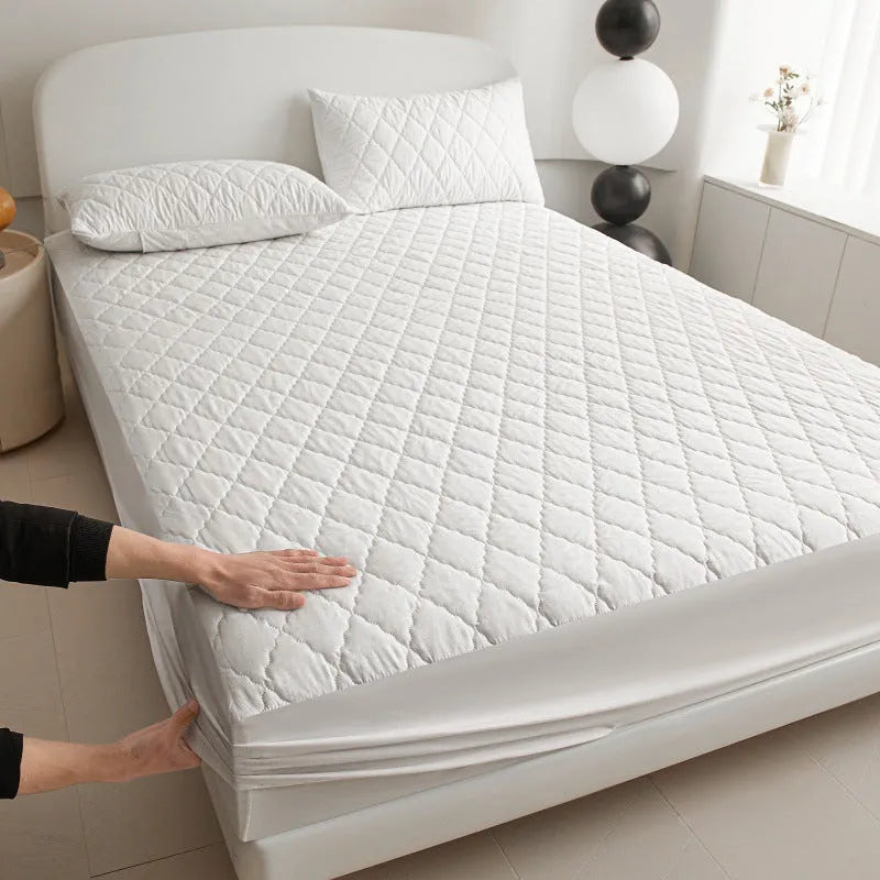 Diamond quilted black waterproof mattress protector fitted sheet and pillowcases set on a bed