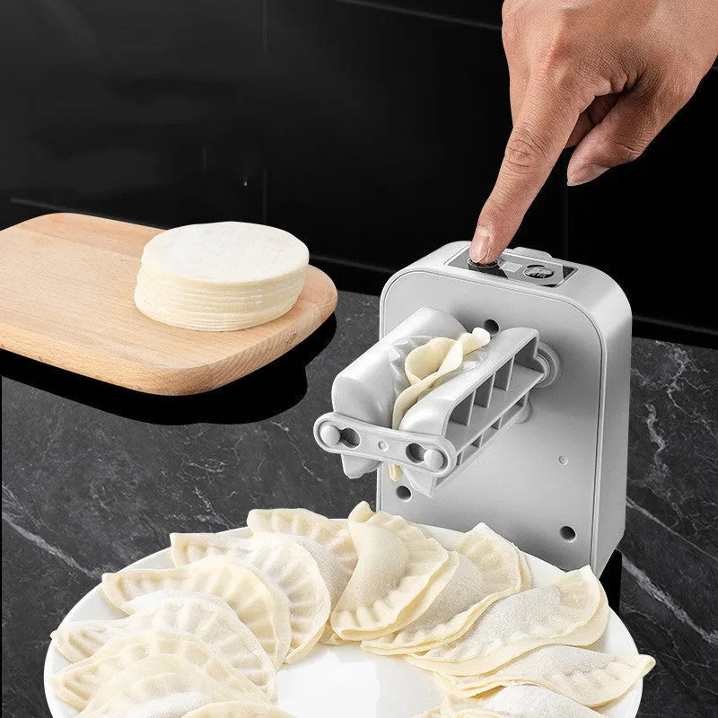 White automatic electric dumpling maker machine with USB charging cable, brush, and spoon on a kitchen counter.