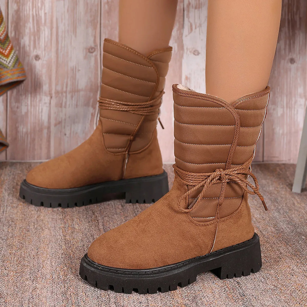 A pair of women's chunky heel snow boots in suede with a lace-up front and fleece lining, shown in black.