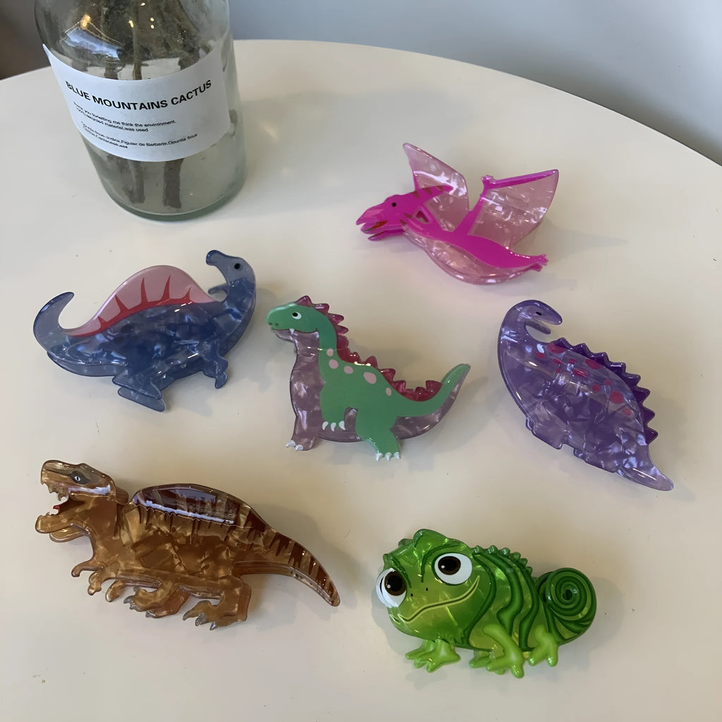 Acrylic dinosaur jaw hair clip showing six colour variations with grip-style fastening mechanism