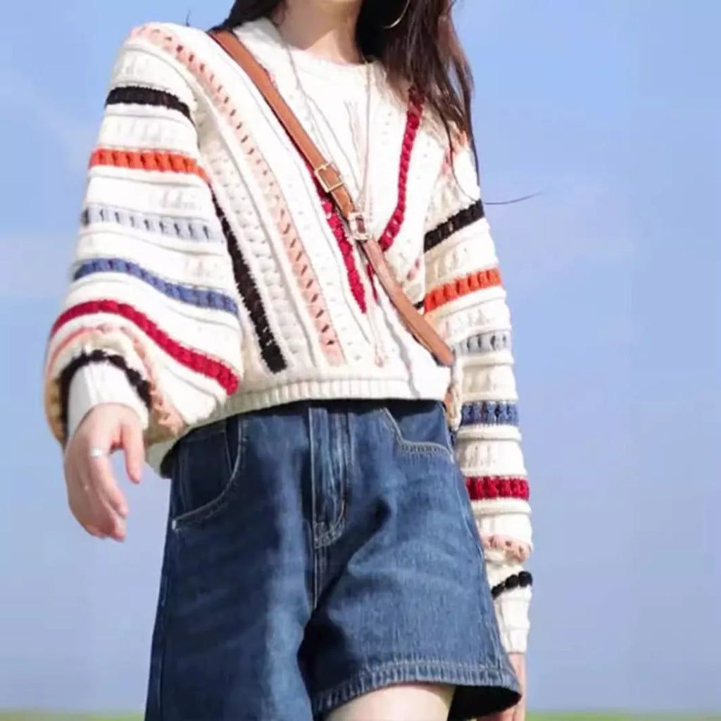 Retro rainbow striped hollow pullover sweater with batwing sleeves on a hanger.