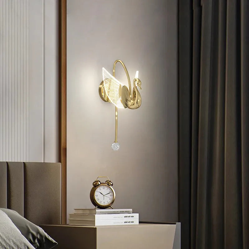 Gold modern swan-shaped bedside wall lamp with an acrylic shade mounted on a wall.