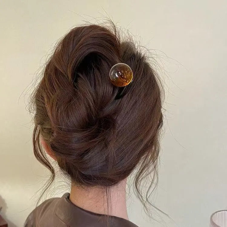A set of U-shaped acrylic hair barrettes with a ball detail in beige, caramel, dark grey, and green colours