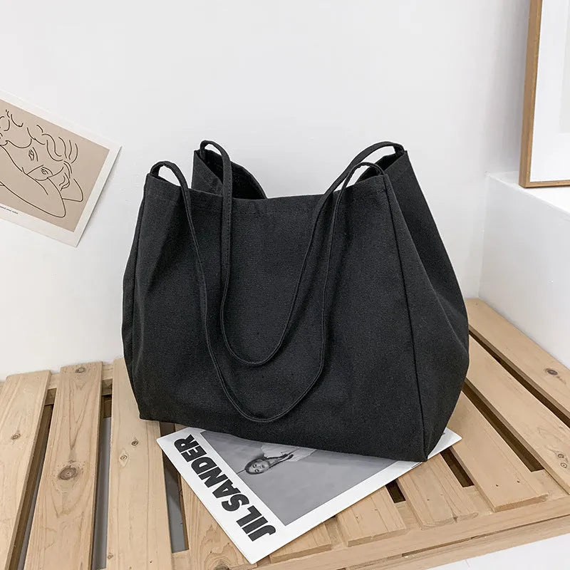 Women's solid colour canvas handbag showing horizontal square shape and double shoulder straps