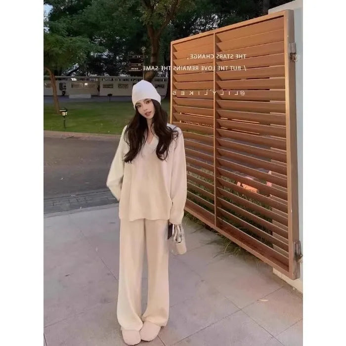 Women's V-neck knitted two-piece suit with wide-leg pants in beige, showing asymmetric pleating on top