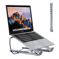 Silver aluminium folding laptop stand with integrated multi-port docking hub on a desk.