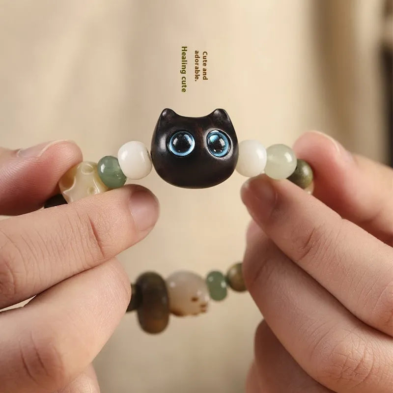 Hand-woven beaded bracelet with bodhi, jade, and ebony beads featuring a cartoon cat's paw charm.