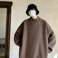 Man wearing a loose grey round neck long sleeve polyester sweater for casual spring or autumn attire.