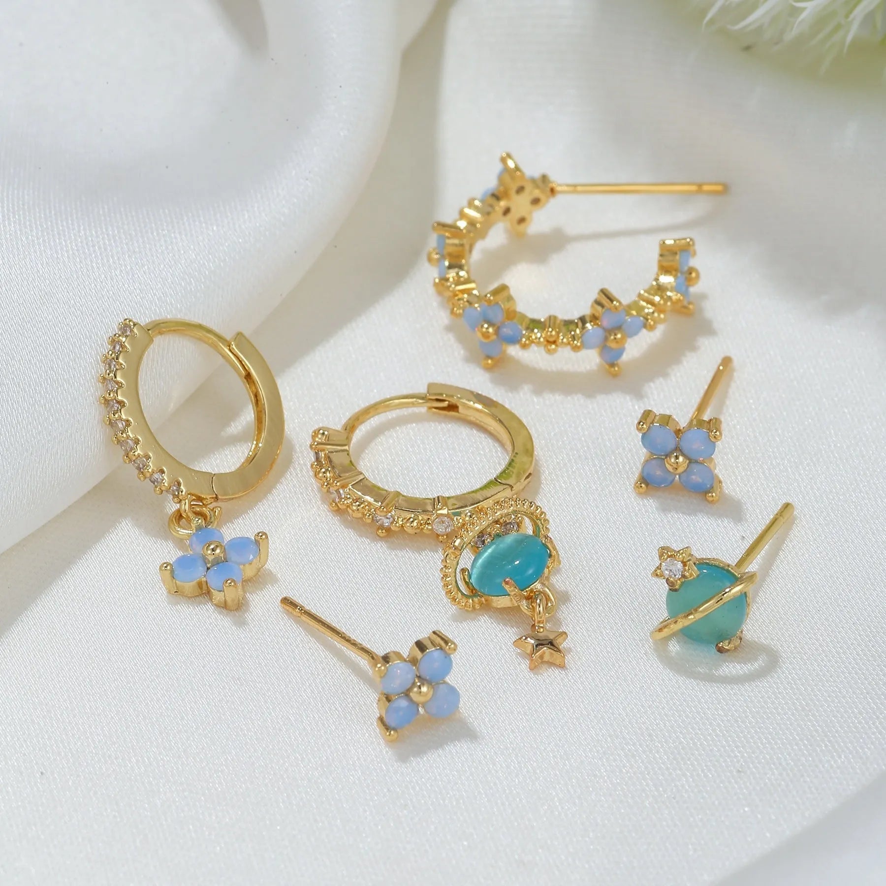 Gold and silver flower-shaped ear studs with zircon mosaic detail on a white background.