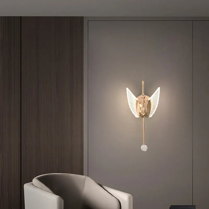 Gold modern swan-shaped bedside wall lamp with an acrylic shade mounted on a wall.