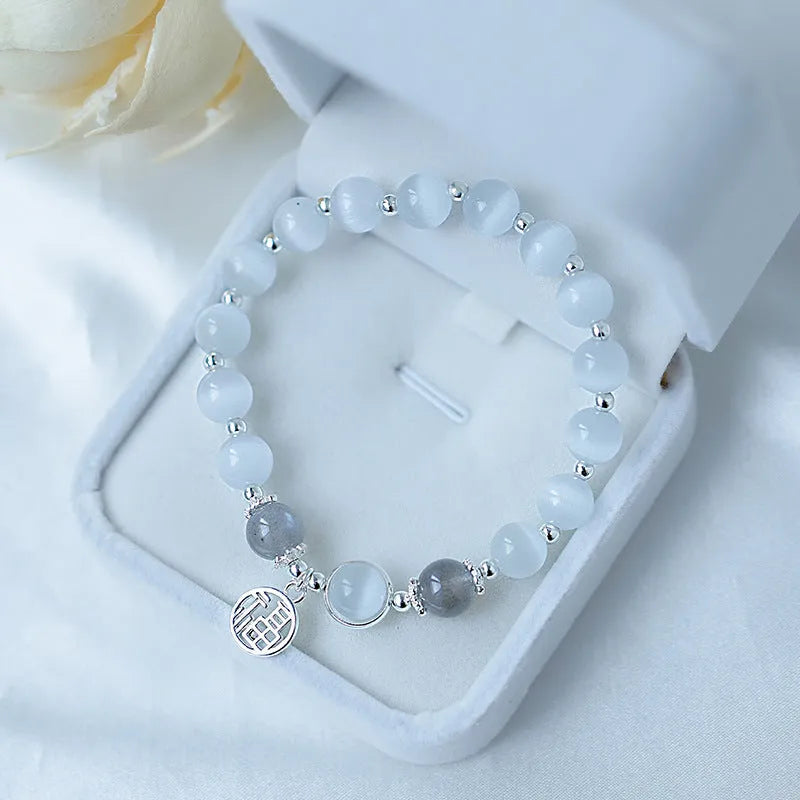 Close-up of a women's opal cat's eye stone beaded bracelet with diamond-shaped beads on a wrist.