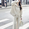 Woman wearing a beige knitted zipper cardigan and matching wide-leg trousers from a two-piece co-ord set.