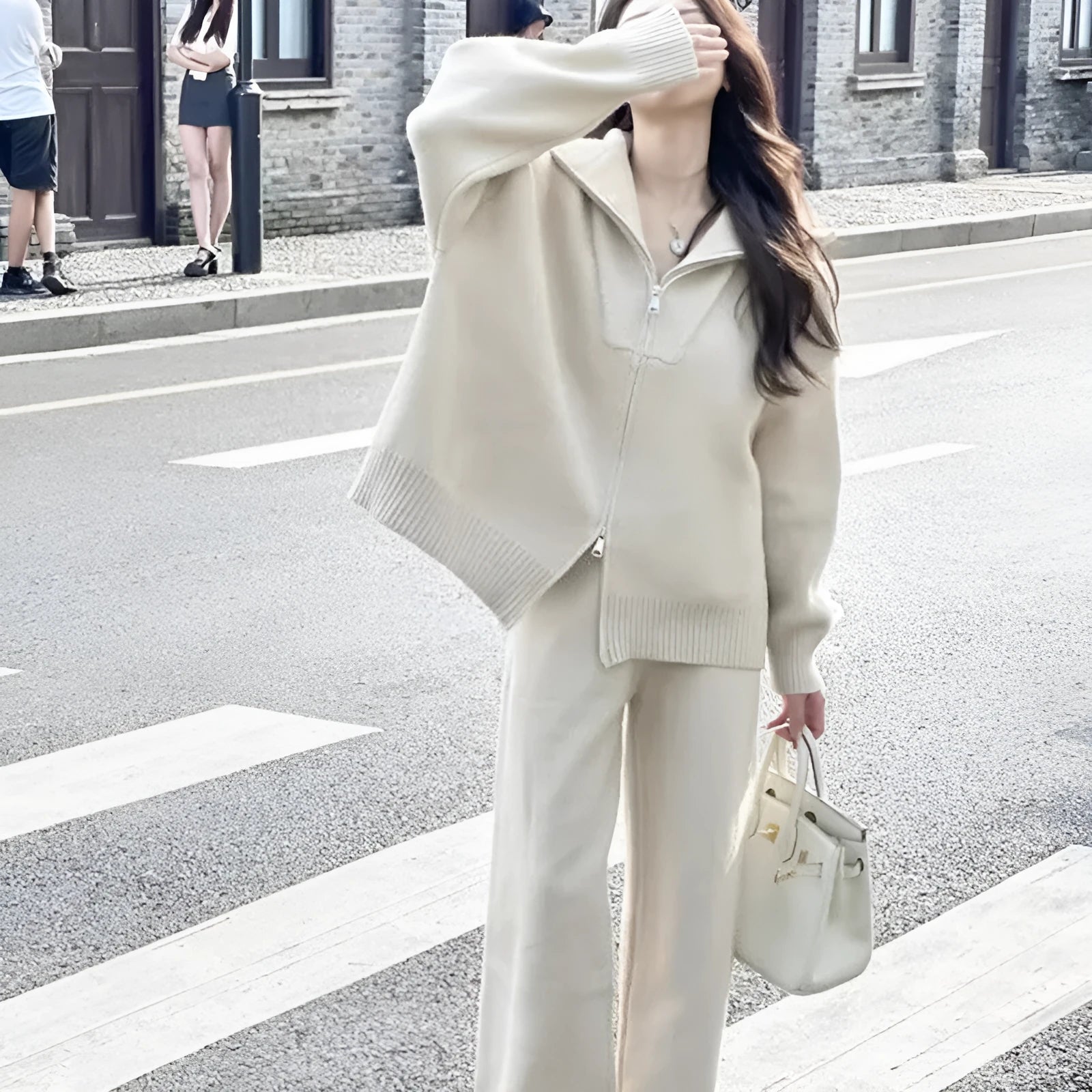 Woman wearing a beige knitted zipper cardigan and matching wide-leg trousers from a two-piece co-ord set.