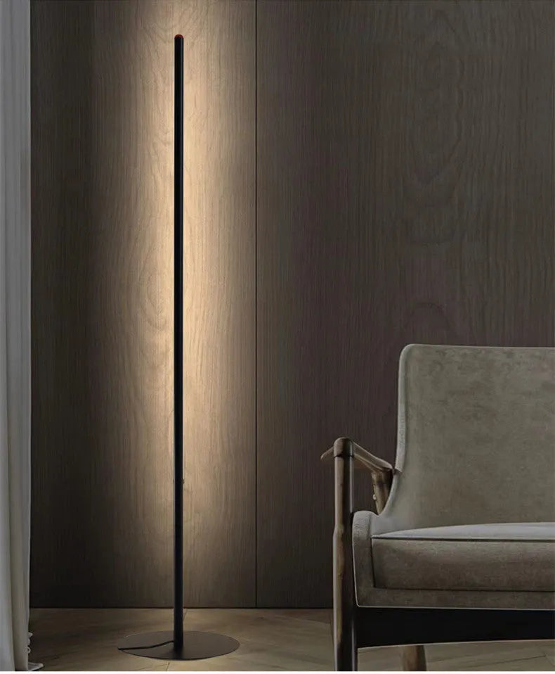 Slender vertical aluminium alloy LED floor lamp in a modern design next to a sofa.