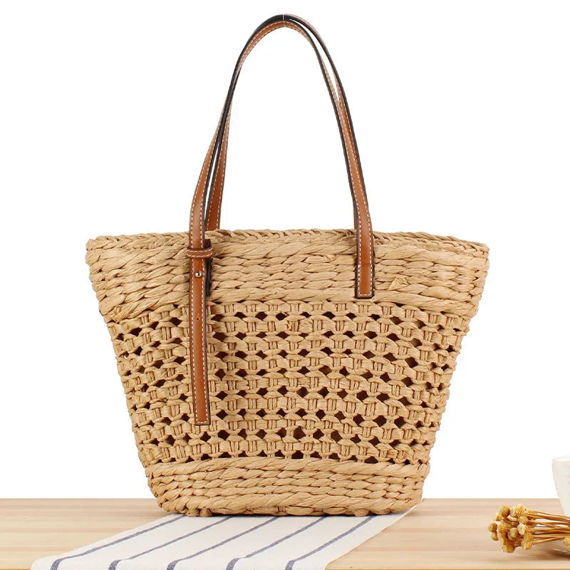 Paper woven shoulder bag with adjustable strap in beige colour showing horizontal square shape and straw decorative elements