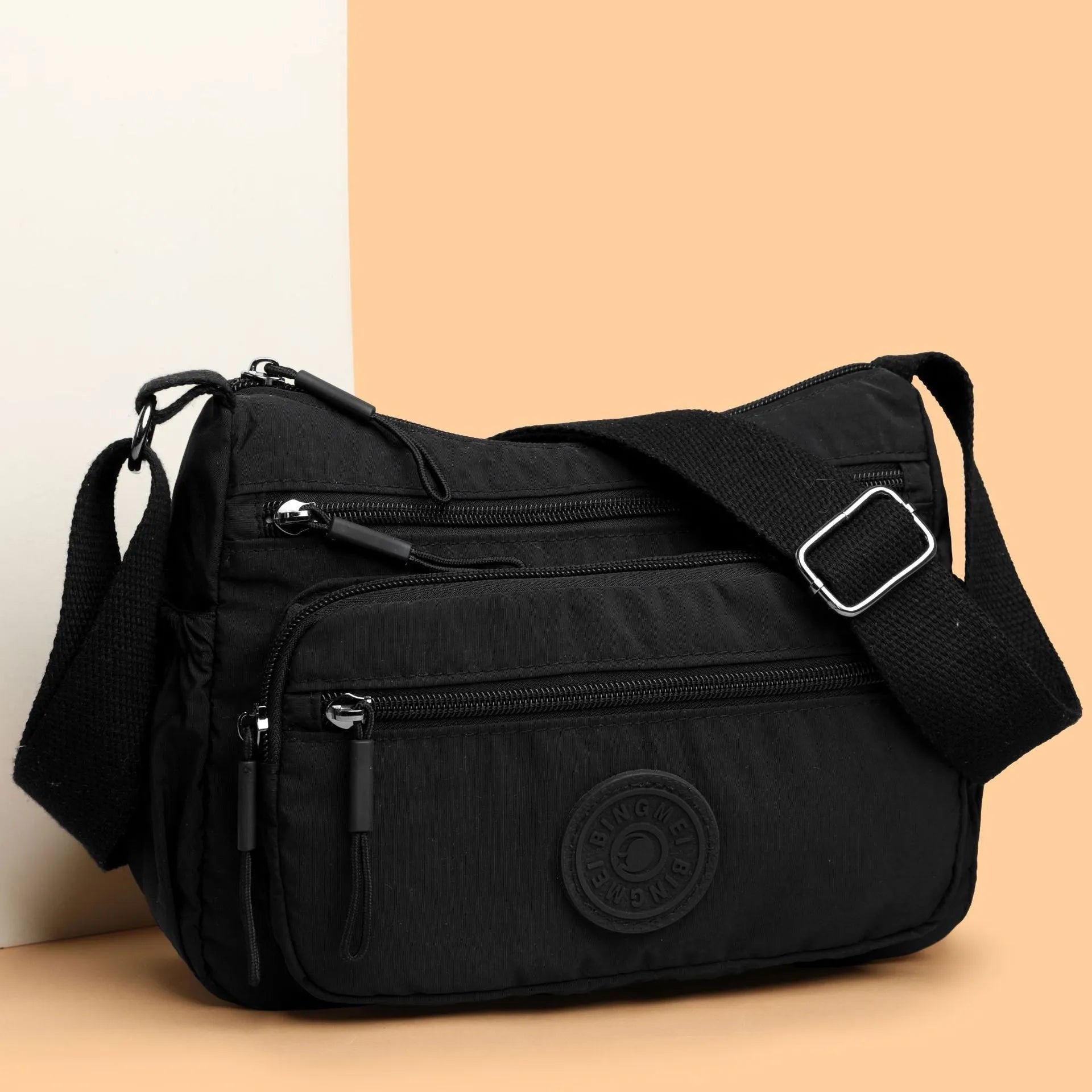 Soft nylon crossbody bag in black, grey, or red with a single shoulder strap and water-repellent finish.