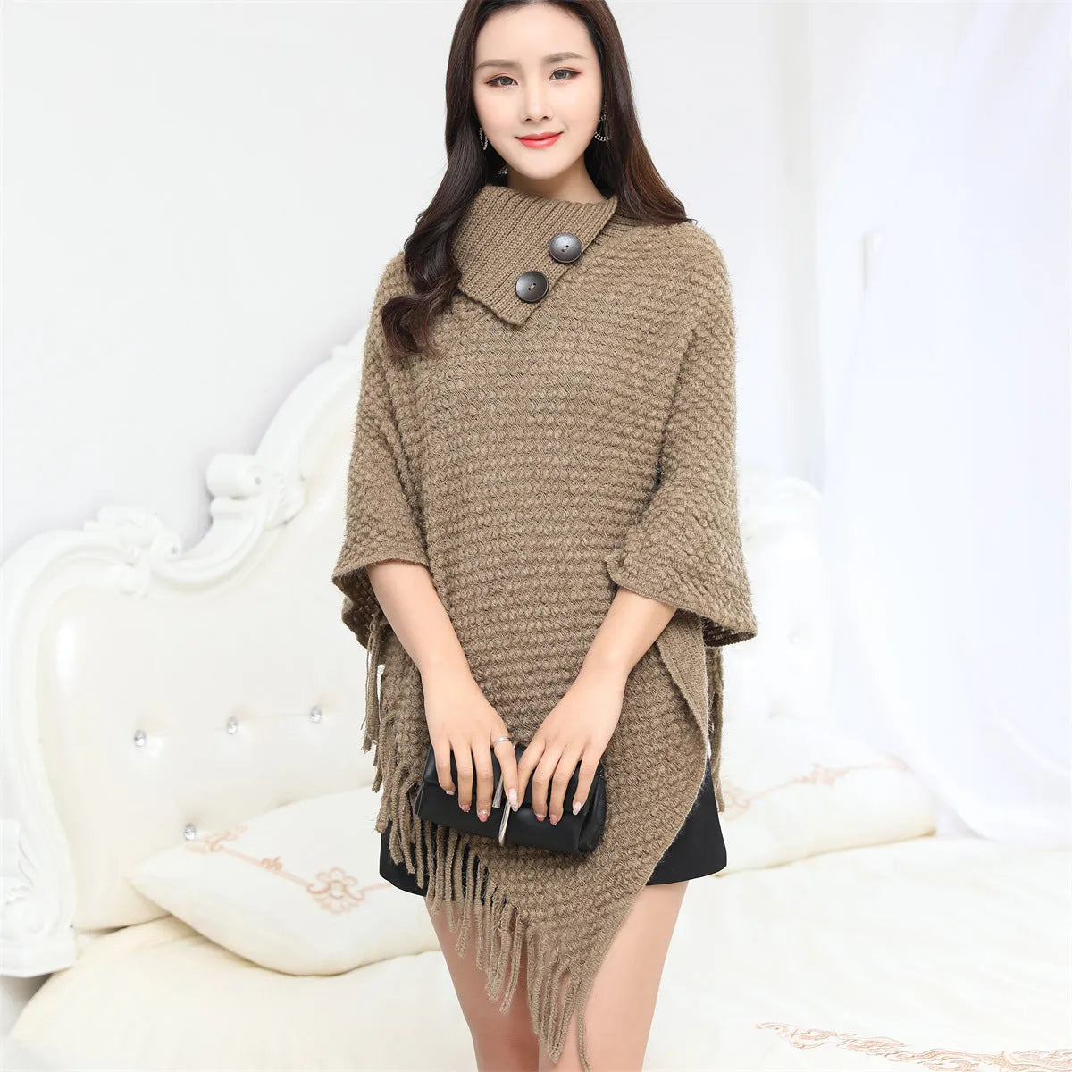 Sleeveless polka dot knit cloak in apricot colour, shown as a vest on a hanger.