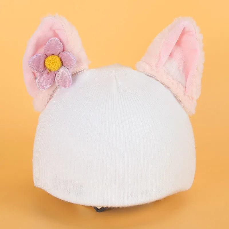 Soft plush cartoon character topper fitting over a blue ski helmet on a snowy background.