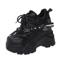 Women's white and black platform sports shoes with cross strap and rubber sole.