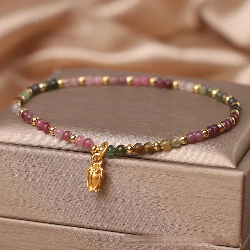 Natural tourmaline bead anklet for women with a silver flower charm on an ankle.