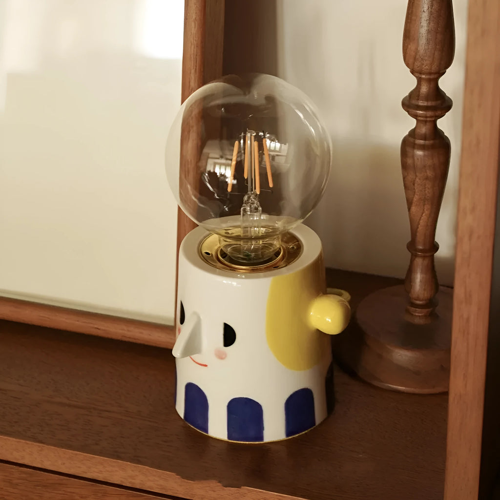 Handmade ceramic ball headlight lamp with a white glaze and integrated UK plug on a wooden table.