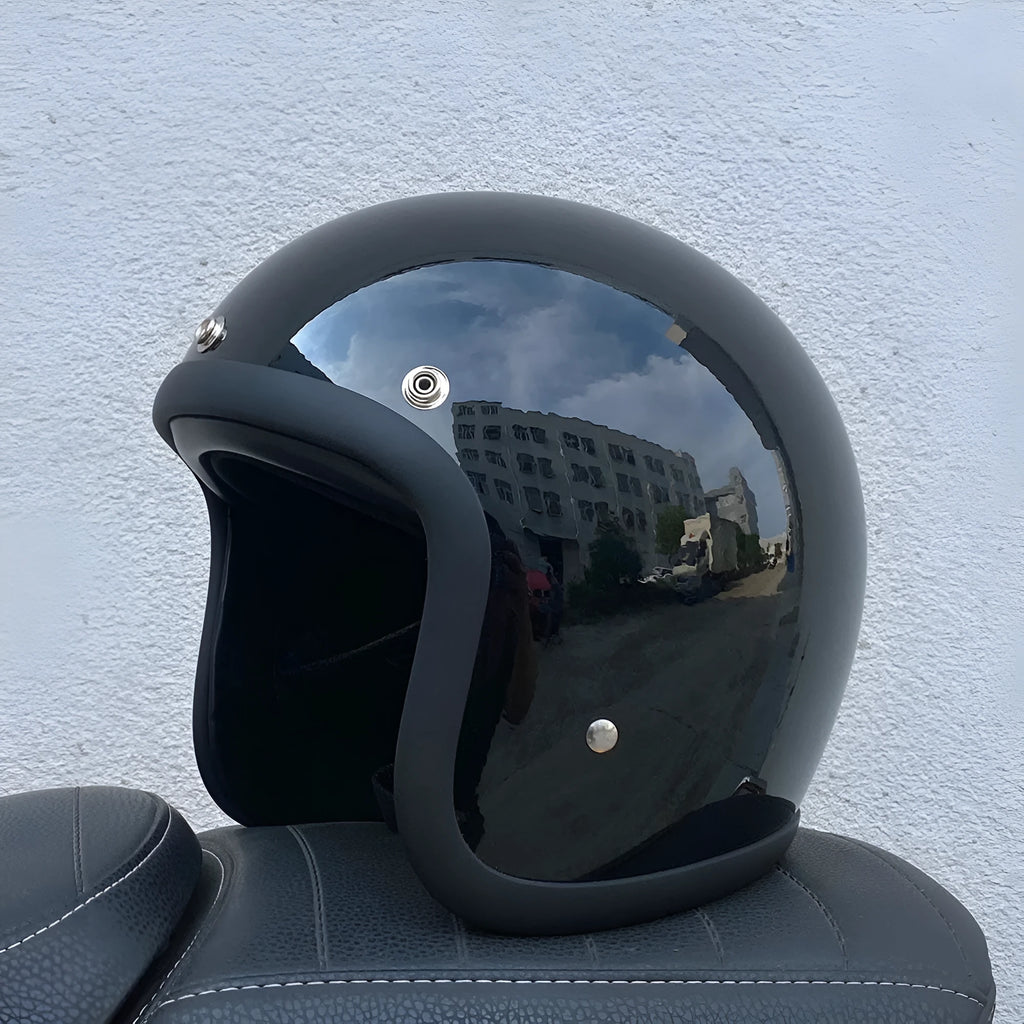 Retro-style open-face motorcycle helmet in matte black with floral design, showing clear visor and interior padding.