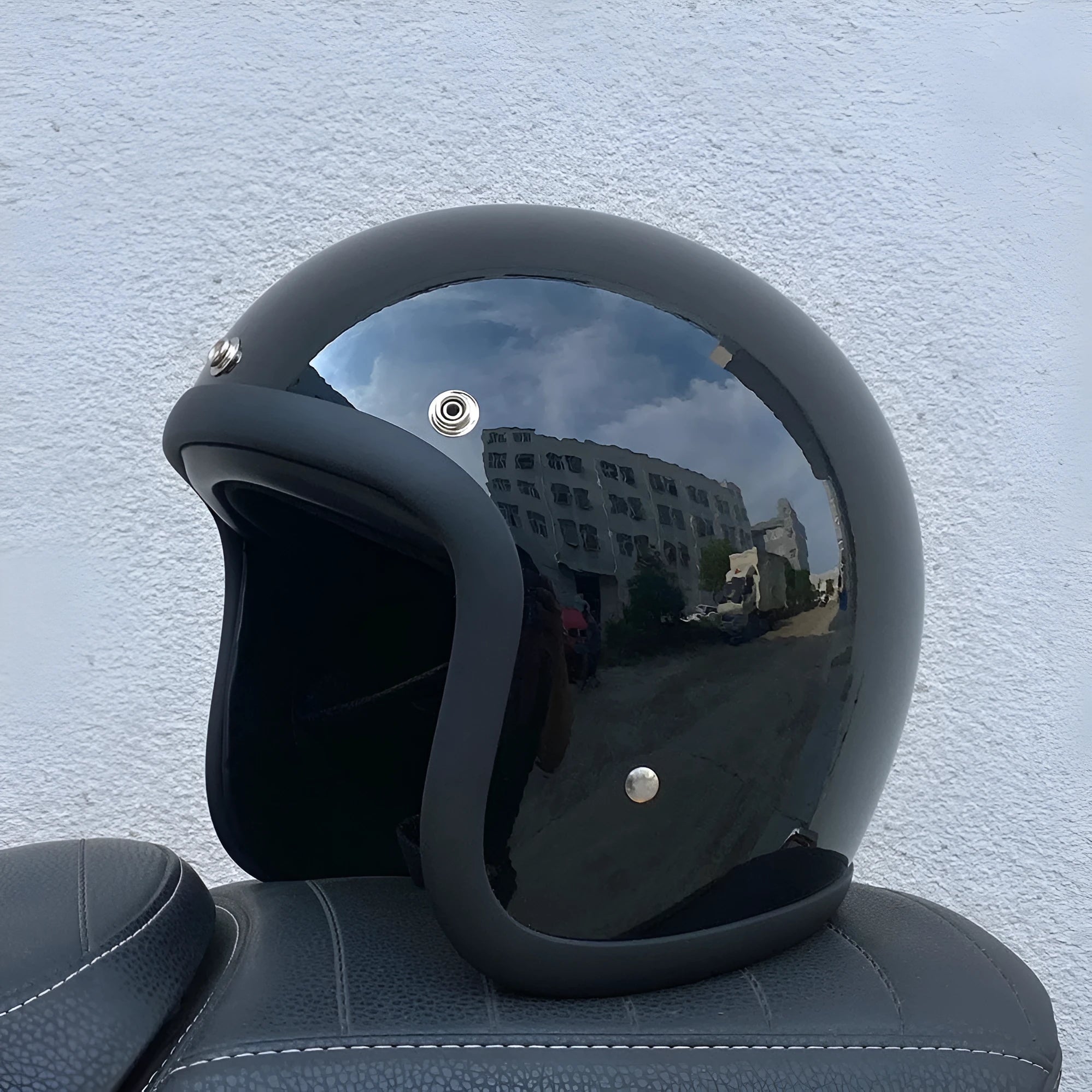 Retro-style open-face motorcycle helmet in matte black with floral design, showing clear visor and interior padding.