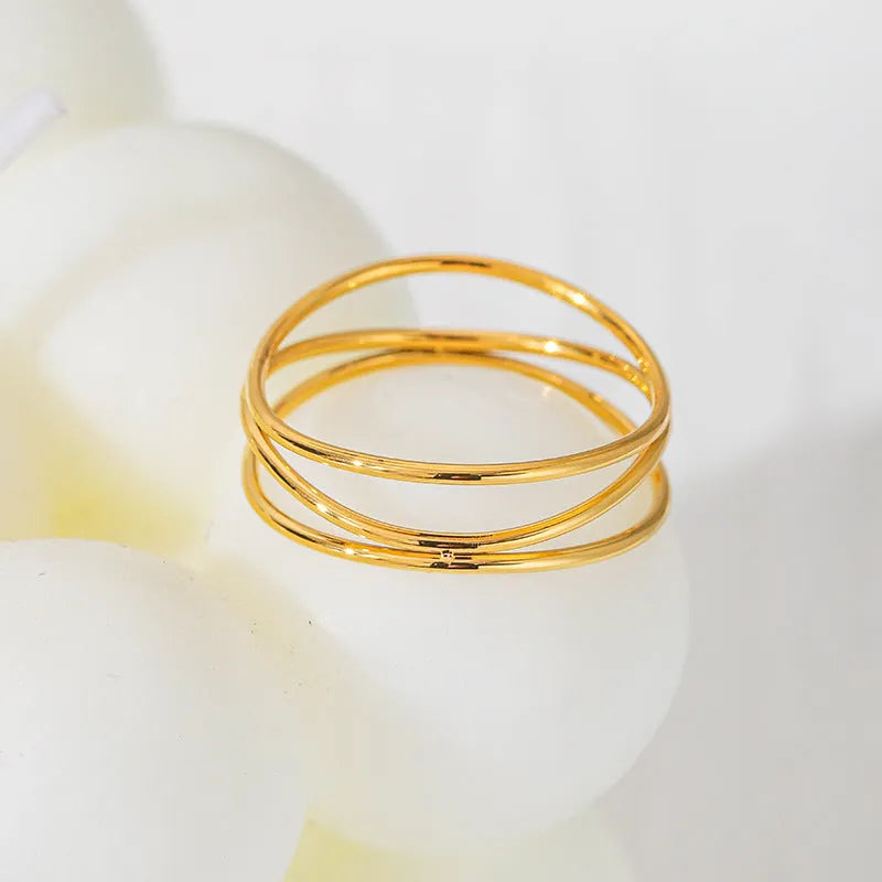 Gold titanium steel geometric ring with a three-layer coil design on a plain background.