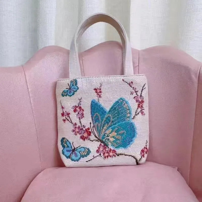 Double-sided embroidered canvas tote bag with gold wire trim, shown in a selection of seven colourways.