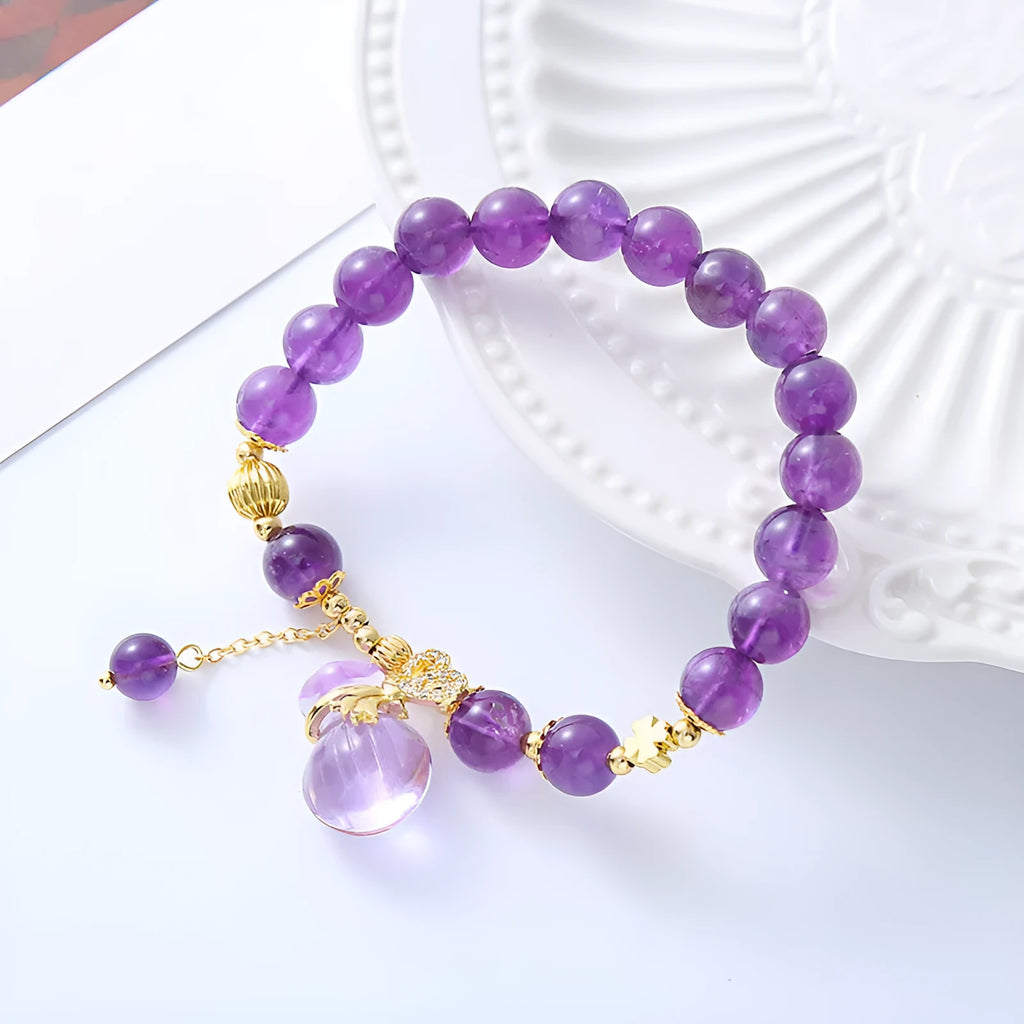 Purple amethyst crystal bracelet with money bag charm and peace buckle on woman's wrist